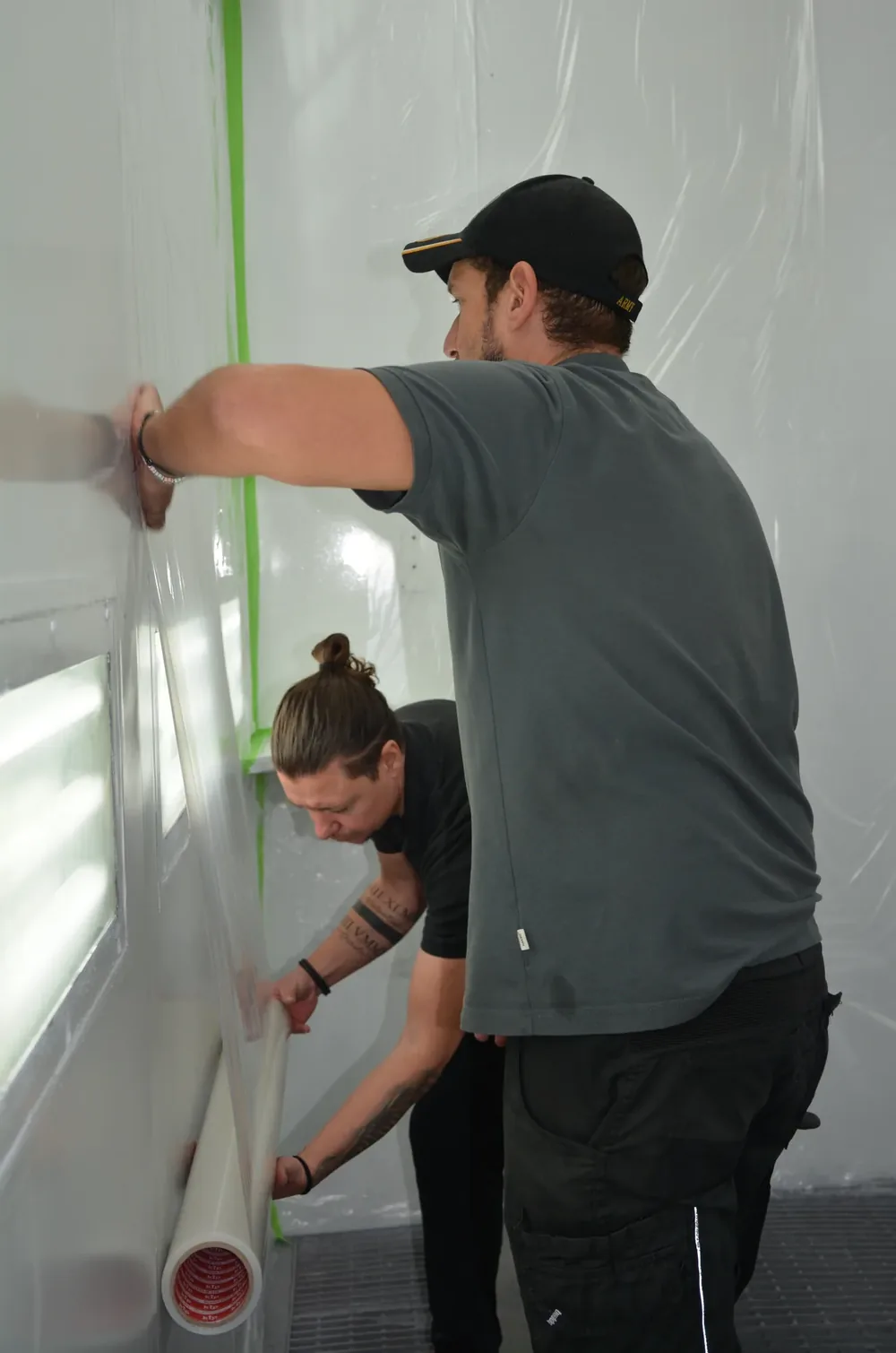 Zwei Mitarbeiter der KSK Objektservice GmbH beim Abkleben einer Lackierkabine
